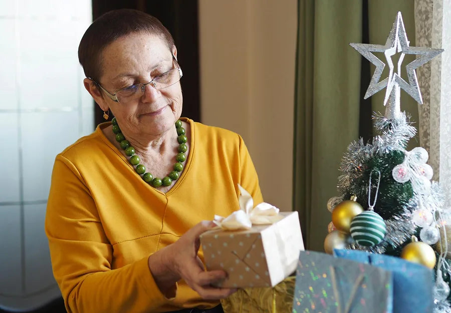 An elderly woman with dementia holding a wrapped holiday gift