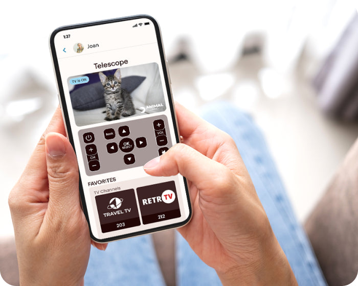 woman holding a mobile phone using the JubileeTV app to control her elderly mother's tv remotely - she sees what's  playing on the tv, which is a video of a kitten.