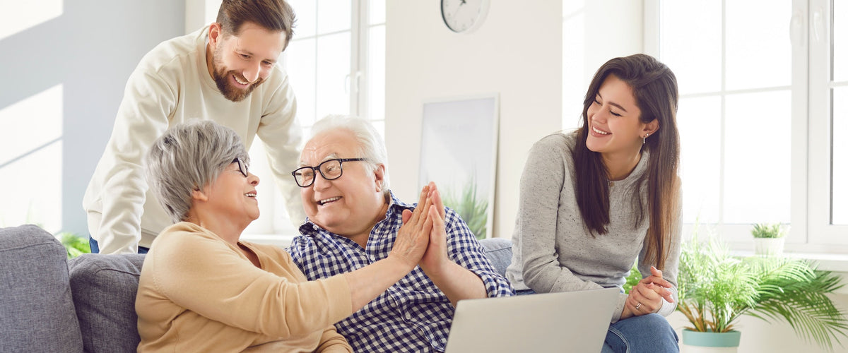 Caretakers helping older couple use laptop with tech tips for seniors