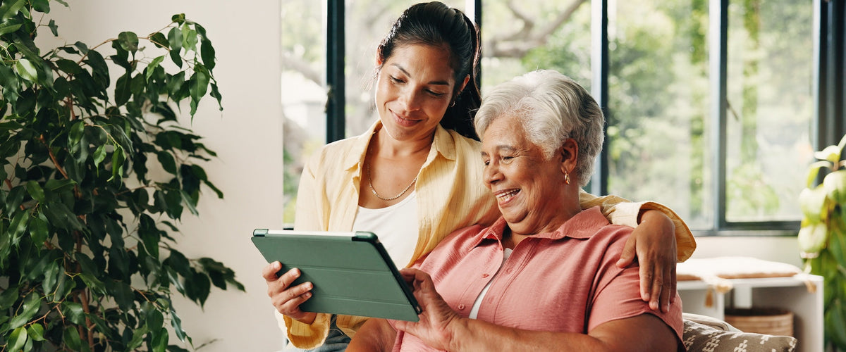 Daughter connecting with senior mother through tablet elderly monitoring device