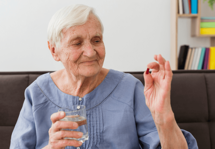 An elderly woman is taking medication over video call