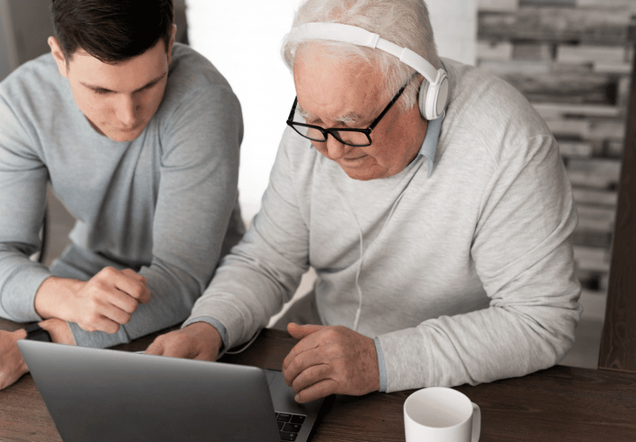 an elderly man learning technology from his grandson