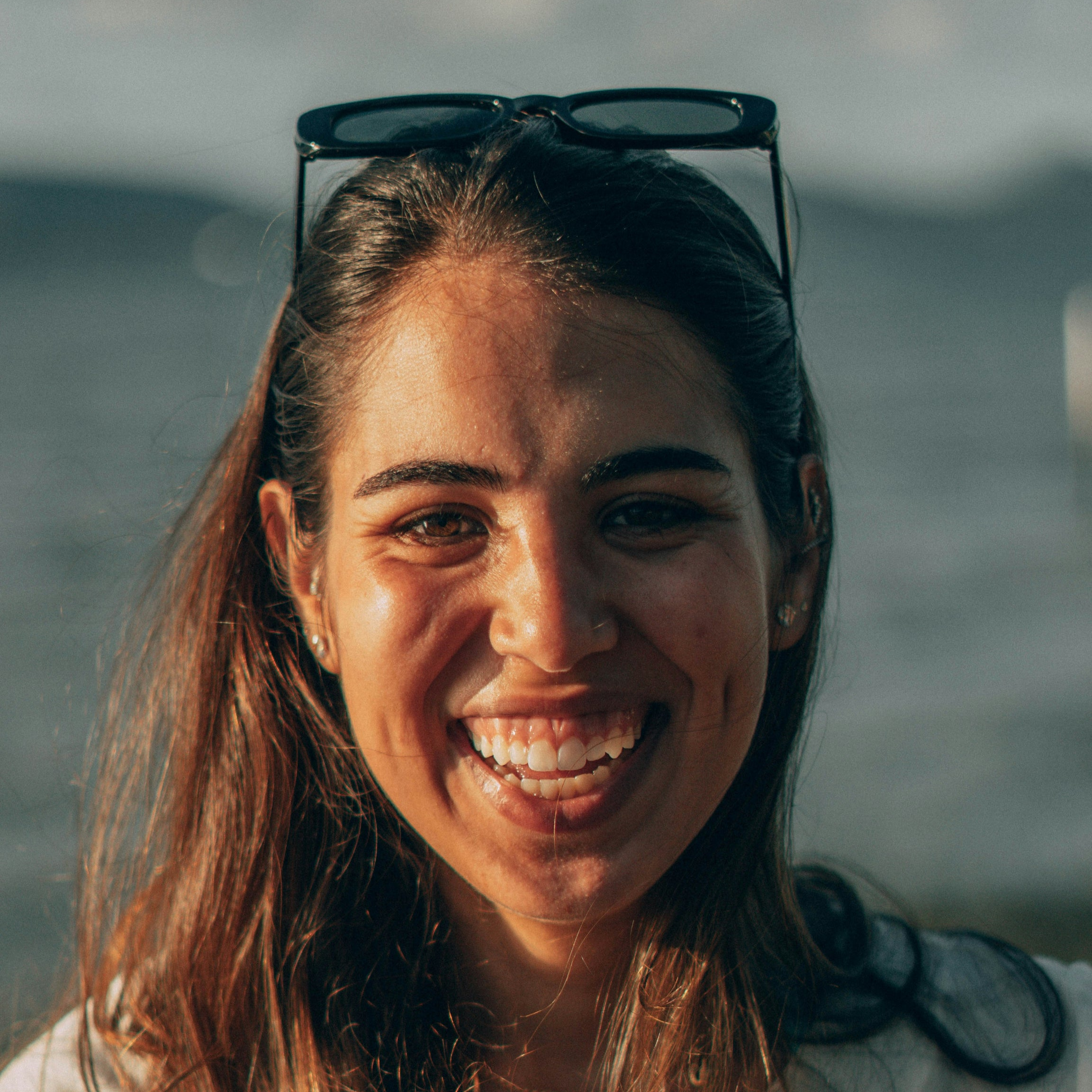 A woman smiling with sunglasses on her head.