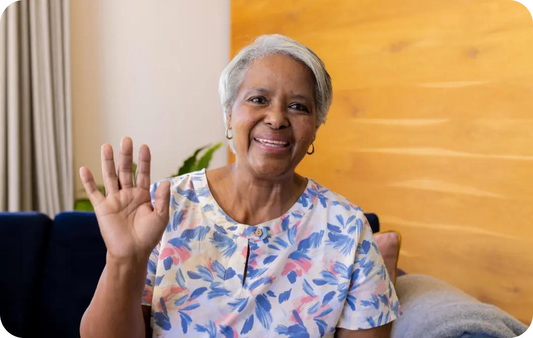 happy elderly woman waving from her couch