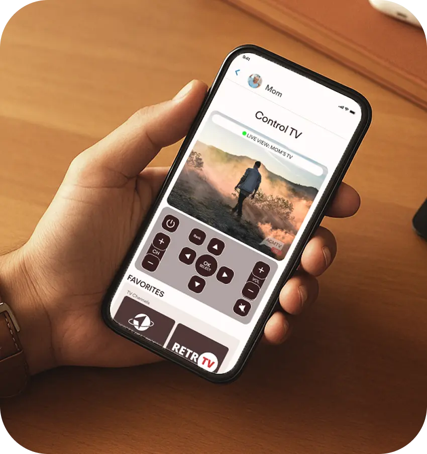 Hand holding a smartphone controlling elderly mother's TV remotely with the JubileetTV app