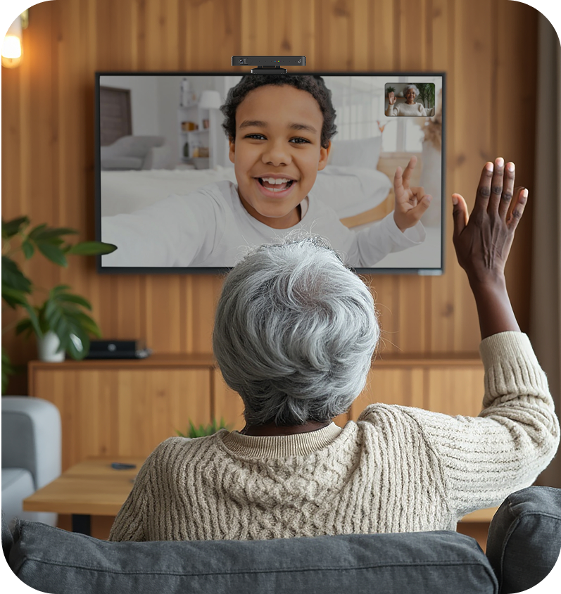 Person sitting on a couch in a living room, watching a child on a screen.