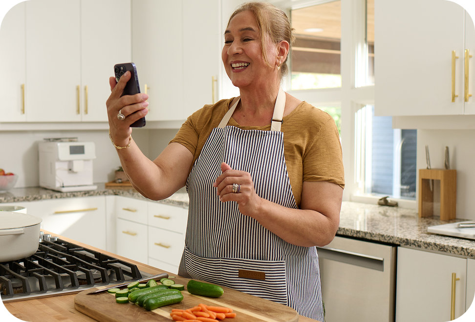 Woman in a kitchen video calling with her elderly parent.