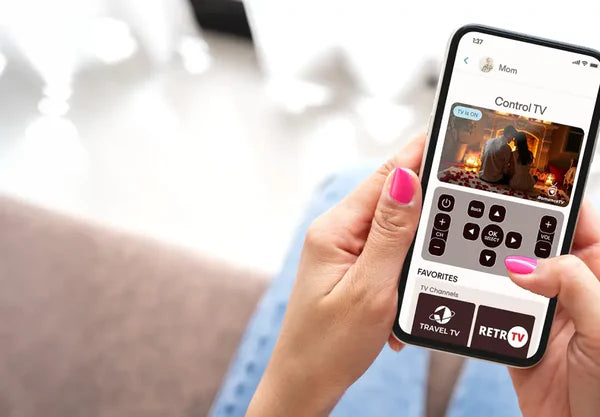 Person holding a smartphone with a TV control app displayed in a home setting.