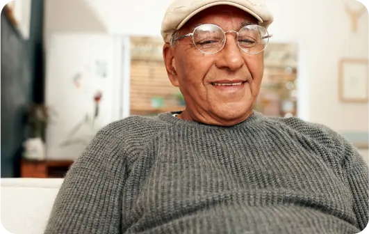 happy elderly man wearing glasses is sitting on a couch