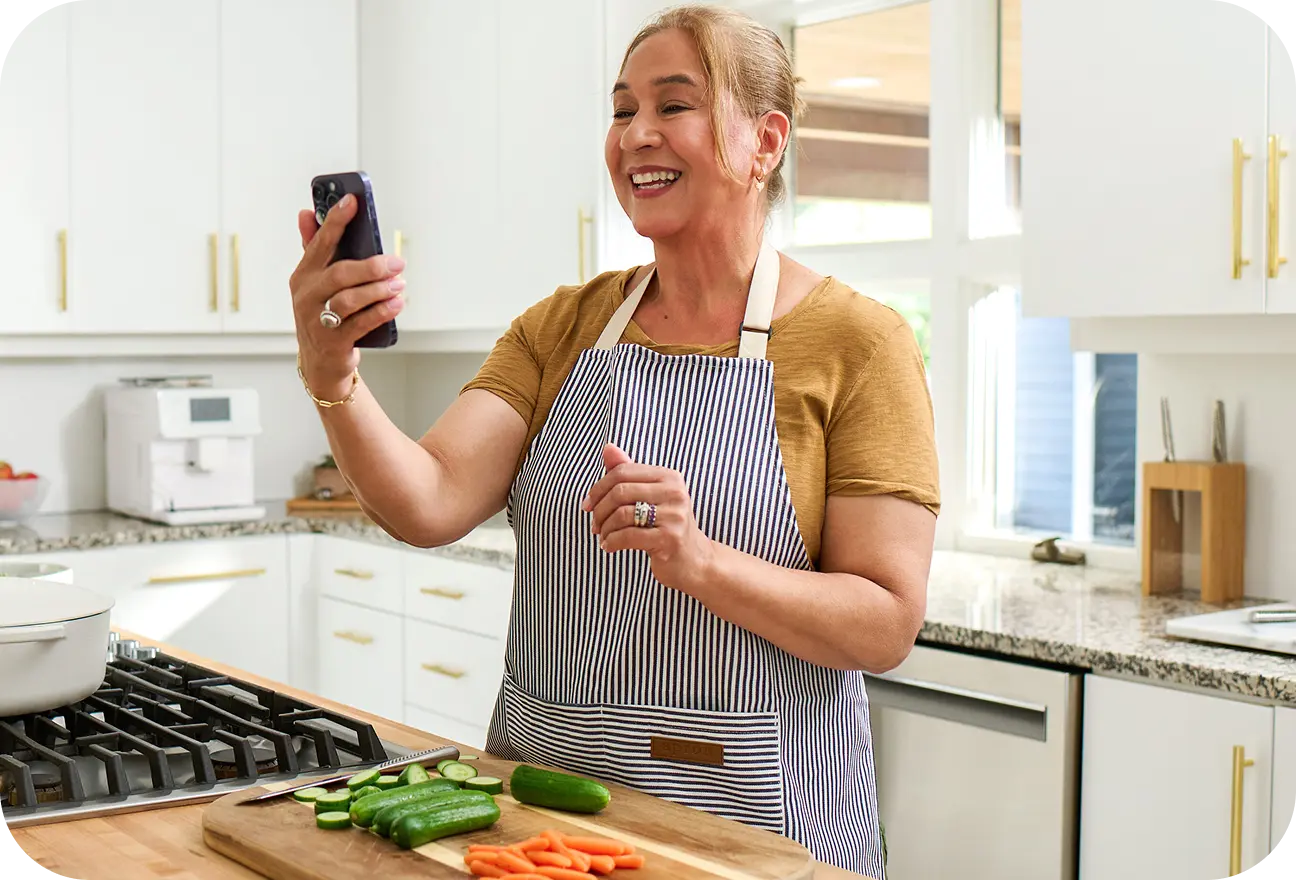 Woman in a kitchen video calling with her elderly parent.
