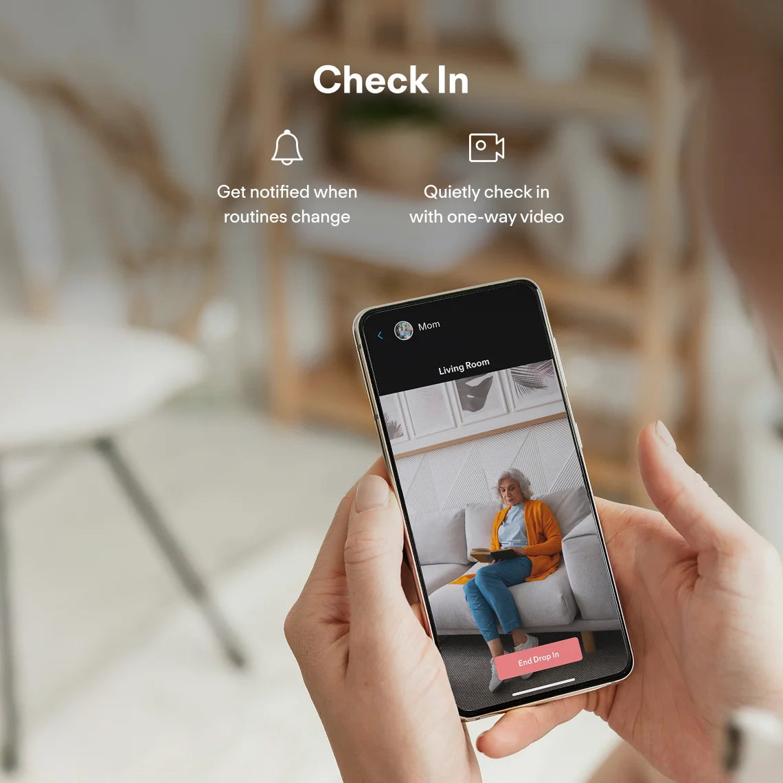 Person using a smartphone app for elderly monitoring device feature in a living room setting.