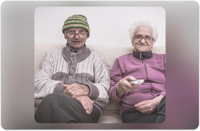 elderly couple sitting on couch watching tv