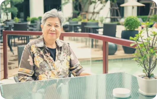 elderly woman sitting at a table outside