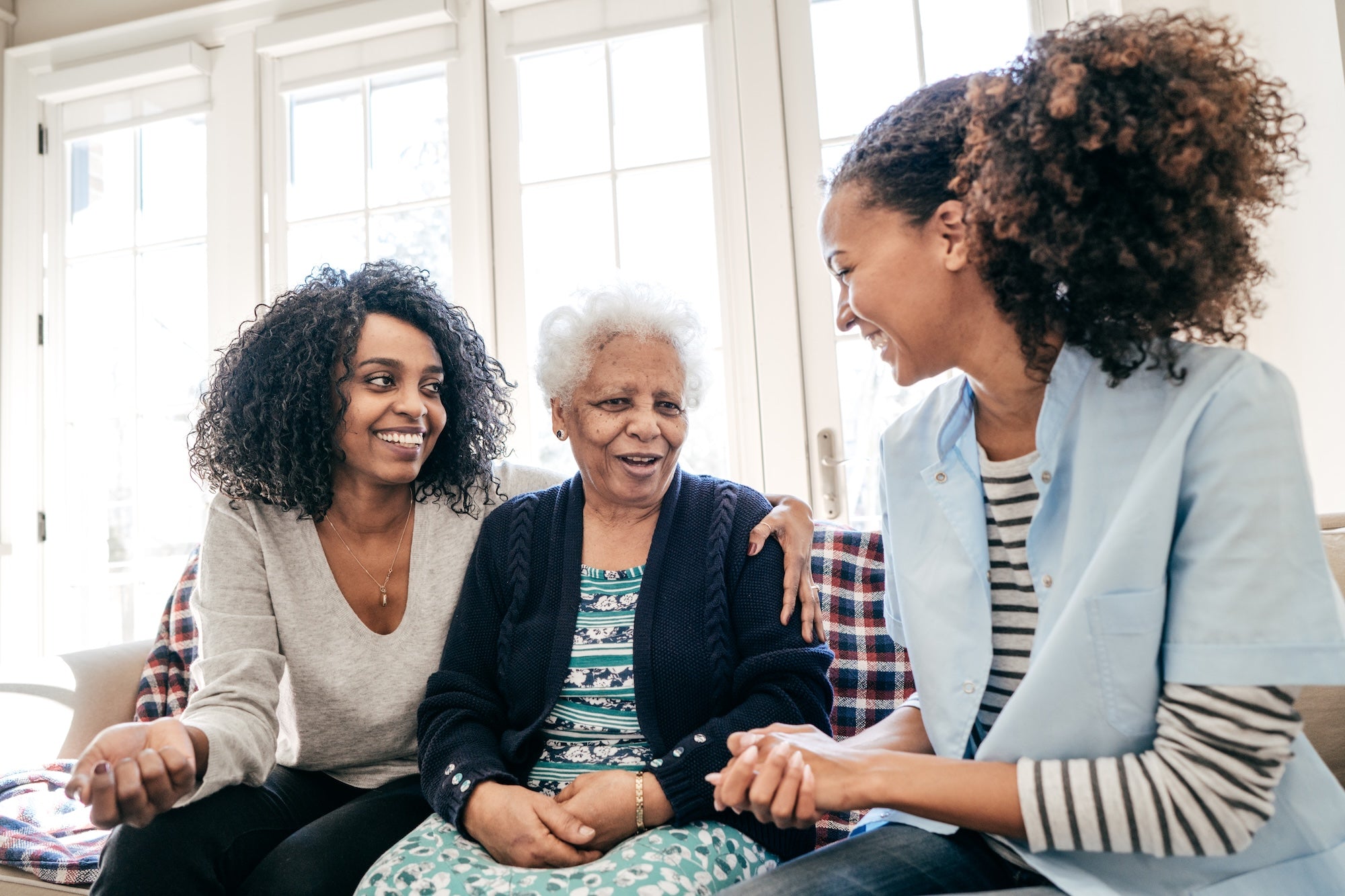Three women sitting together, smiling and engaged in conversation.