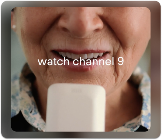 elderly woman using voice control to change channels on the tv